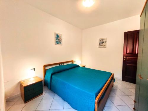 a bedroom with a blue bed and a night stand at Apartment with Pool and Private Parking in Porto Ottiolu