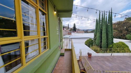 a green house with a balcony with a table at Hotel Colonial Guanajuato in Guanajuato