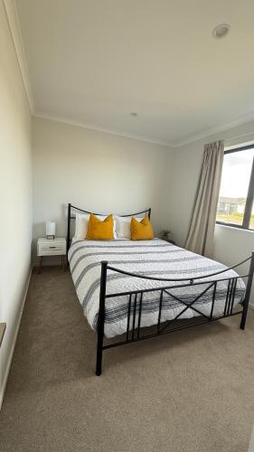 a bedroom with a bed with yellow pillows and a window at Stay with the Singhs in Rolleston