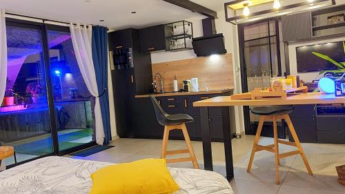 a kitchen with a counter and a table and chairs at GARY Suite - Studio Cosy, Spa et jardin privatif à 4 min de Cambrai in Awoingt