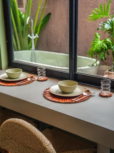 a table with two cups and plates and a window at Patha Canggu in Canggu