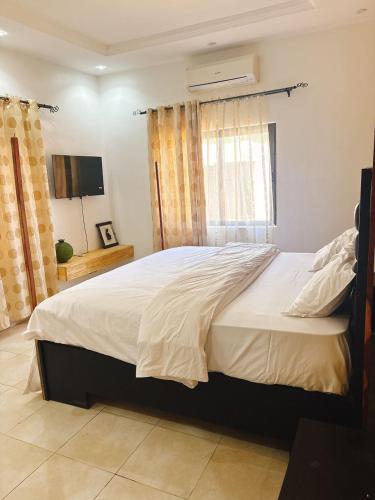 a bedroom with a large white bed with a window at Paradis Douillet in Cotonou