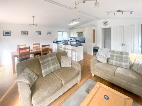 a living room with two couches and a kitchen at Wye Lodge in Aberedw