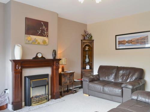 a living room with a leather chair and a fireplace at Serendipity in Keswick
