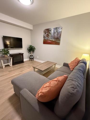 a living room with a gray couch and a flat screen tv at Casa Del Mar-A family Suite in Victoria in Langford