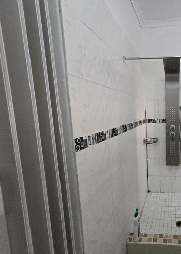 a bathroom with a shower with a toilet and a tile floor at Shado's residence self catering cotages in Serowe