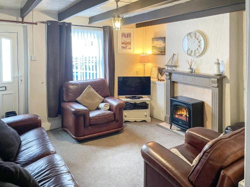 a living room with leather furniture and a fireplace at Billy Napp's Cottage in Filey