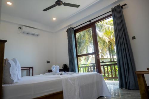 a bedroom with a bed and a large window at Bailey Beach Villa in Ahangama