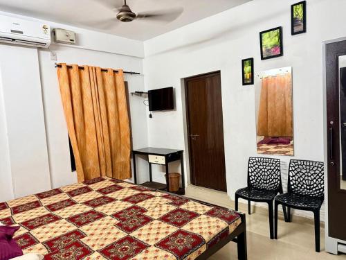 a bedroom with a bed and two chairs and a television at Siva Inn in Guruvāyūr