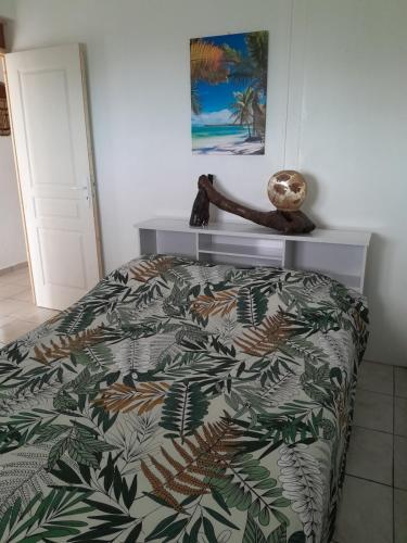 a bedroom with a bed with a green and brown blanket at Coucher de soleil in Bouillante