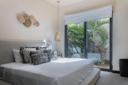 Tulum Villa 2 albercas 4hab hasta 16 personas 10min playa في تولوم: غرفة نوم بها سرير أبيض كبير ونافذة كبيرة