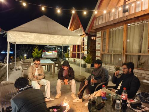 a group of people sitting around a fire on a patio at Parvati valley cottages & cafe in Tosh