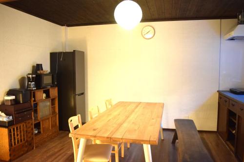 a kitchen with a wooden table and a black refrigerator at Hidasumika Daimon Cozyan in Takayama