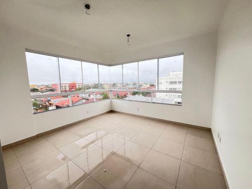an empty room with large windows and white walls at Residencial Palazzo in Tramandaí