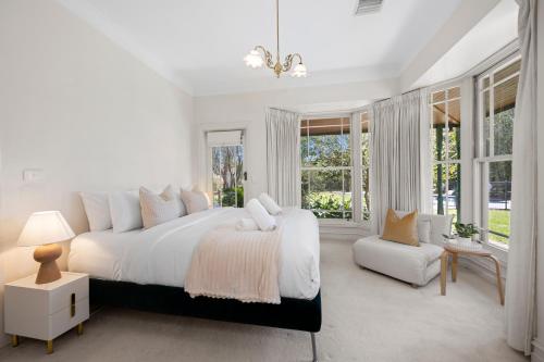 a white bedroom with a large bed and windows at Raygold Park Equestrian Accommodation plus Pool House in Moorooduc