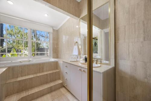 a bathroom with a tub and a sink and a mirror at Raygold Park Equestrian Accommodation plus Pool House in Moorooduc