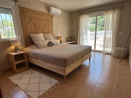 1 dormitorio con 1 cama con cabecero de madera y ventanas en Beautiful villa with pool and stunning view, en Boterías