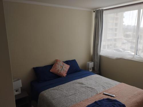 ein Schlafzimmer mit einem Bett mit Kissen und einem Fenster in der Unterkunft Condominio cumbres de reñaca ll in Viña del Mar