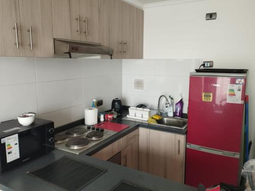 eine Küche mit einem roten Kühlschrank und einer Spüle in der Unterkunft Condominio cumbres de reñaca ll in Viña del Mar
