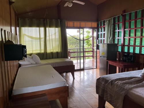 a room with two beds and a kitchen with a balcony at Corcovado Air in Drake