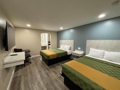 a hotel room with two beds and a desk at Economy Inn - Burbank Airport in Sun Valley