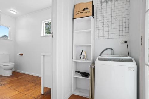 ein Bad mit einer Waschmaschine und einem Trockner im Zimmer in der Unterkunft The Beach Cottage - Close to Beach and Town in Tairua
