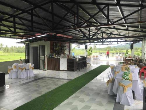 Un salón de banquetes con mesas y sillas blancas. en American Roadhouse Hotel and Restaurant, en Candijay