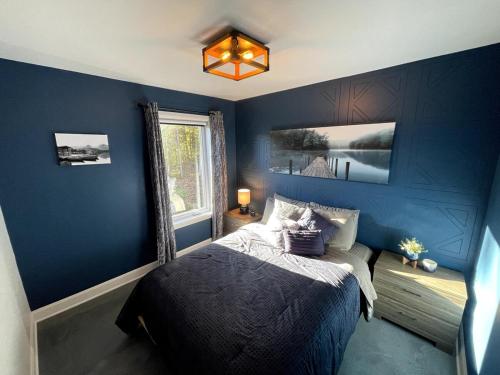 a blue bedroom with a bed and a window at Le SUMMUM in Sainte Anne des Lacs