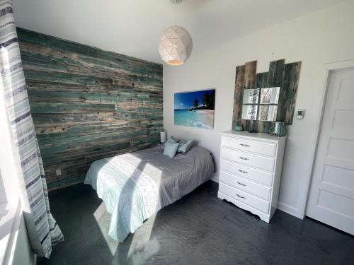a bedroom with a bed and a wooden wall at Le SUMMUM in Sainte Anne des Lacs