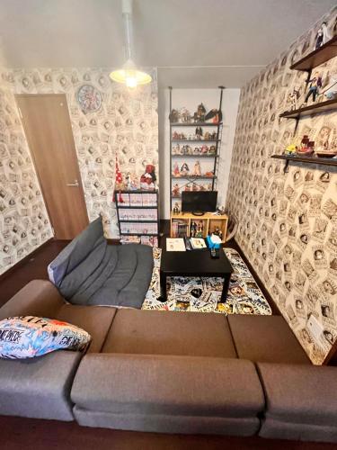 a living room with a brown couch in front of a wall at Tomoeドットコム2 onepiecehouse in Hakodate