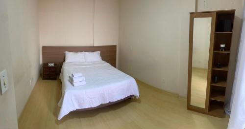a bedroom with a bed with white sheets and a mirror at Apartamento in Viçosa