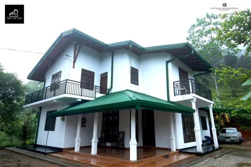 a white house with a green awning at Tea Escape Holiday Villa and Cabanas in Gampola