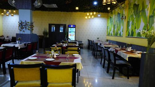 uma sala de jantar com mesas e cadeiras em um restaurante em Hotel Manas Plus em Khandwa