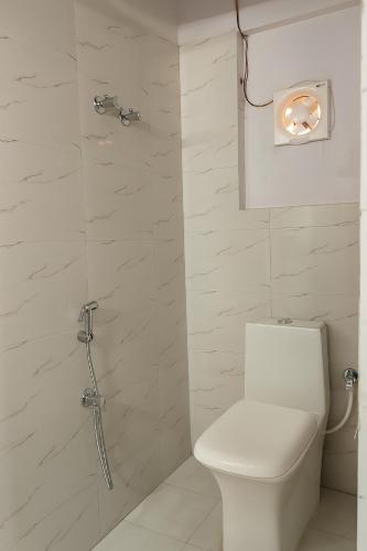a white bathroom with a toilet and a shower at Vinayaka Heritage in Patna