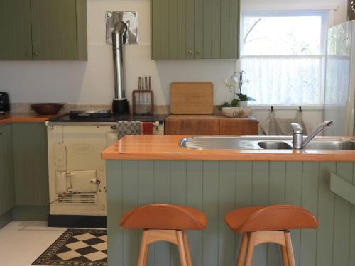 a kitchen with green cabinets and two bar stools at Lola in Palm Beach