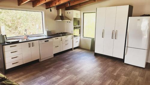 Una cocina con gabinetes blancos y una ventana grande. en Paradise HQ Pukenui, en Pukenui