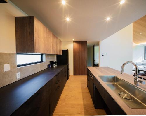 a kitchen with wooden cabinets and a stainless steel sink at Kamuy Chalet Hakuba by Jade Group in Hakuba