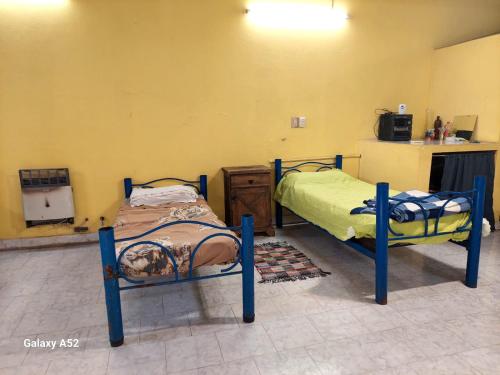 zwei Einzelbetten in einem Zimmer mit Küche in der Unterkunft Depto en arrecifes in Arrecifes