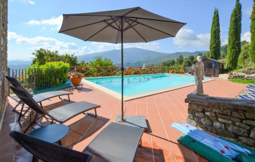 a patio with chairs and an umbrella next to a pool at Amazing Apartment In Caprese Michelangelo in Caprese Michelangelo