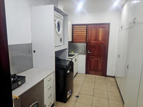 a small kitchen with a brown door and a refrigerator at Barret Lodge in Suva