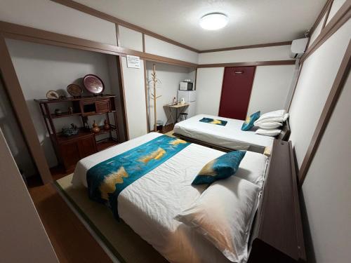 a bedroom with two beds with blue pillows at 福宿 Fukuinn 102号室 in Takamatsu