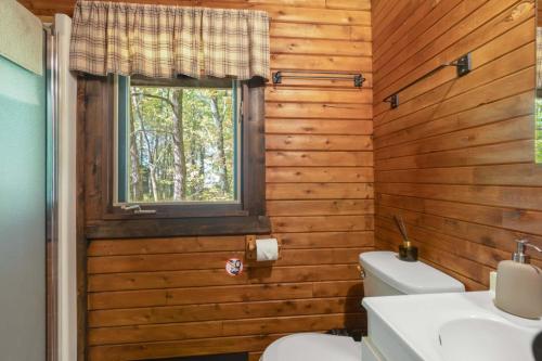 a bathroom with wooden walls and a toilet and a window at chalet 2 - Domaine de l'Archipel in Sorel