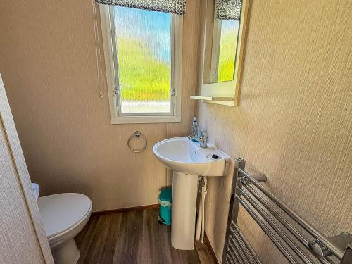 ein Badezimmer mit Waschbecken und Toilette und einem Fenster in der Unterkunft Beautiful 6 Berth Caravan For Hire With Huge Decking At Manor Park Ref 23142K in Hunstanton