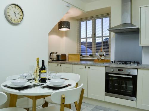 a kitchen with a table and a clock on the wall at Pear Tree Cottage in Bowness-on-Windermere