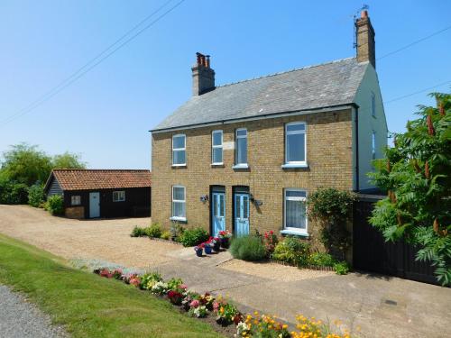 een stenen huis met bloemen ervoor bij Greenbank Cottage in Hilgay