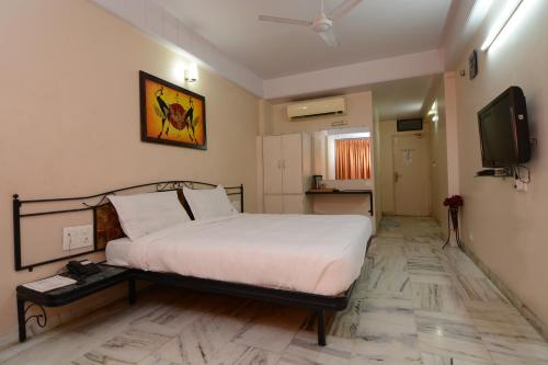 a bedroom with a bed and a flat screen tv at Hotel Vrandavan in Nagpur