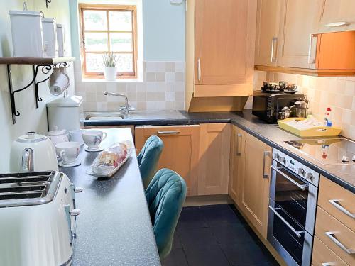 a kitchen with wooden cabinets and a counter top at Lily Rose Cottage in Lanercost