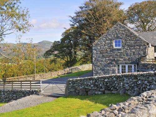 a stone house with a stone fence and a stone wall at Cwm Nantcol Barn in Llanbedr