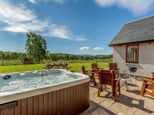 a hot tub on a patio with a table and chairs at Sunnyside House in Duthil