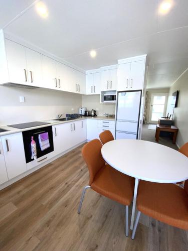 a white kitchen with a white table and chairs at Birch Court - Harakeke in Whanganui